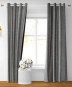 Grey Maya curtains from The Digital Kart hanging in a window with soft natural light, showcasing elegant fabric and modern design.